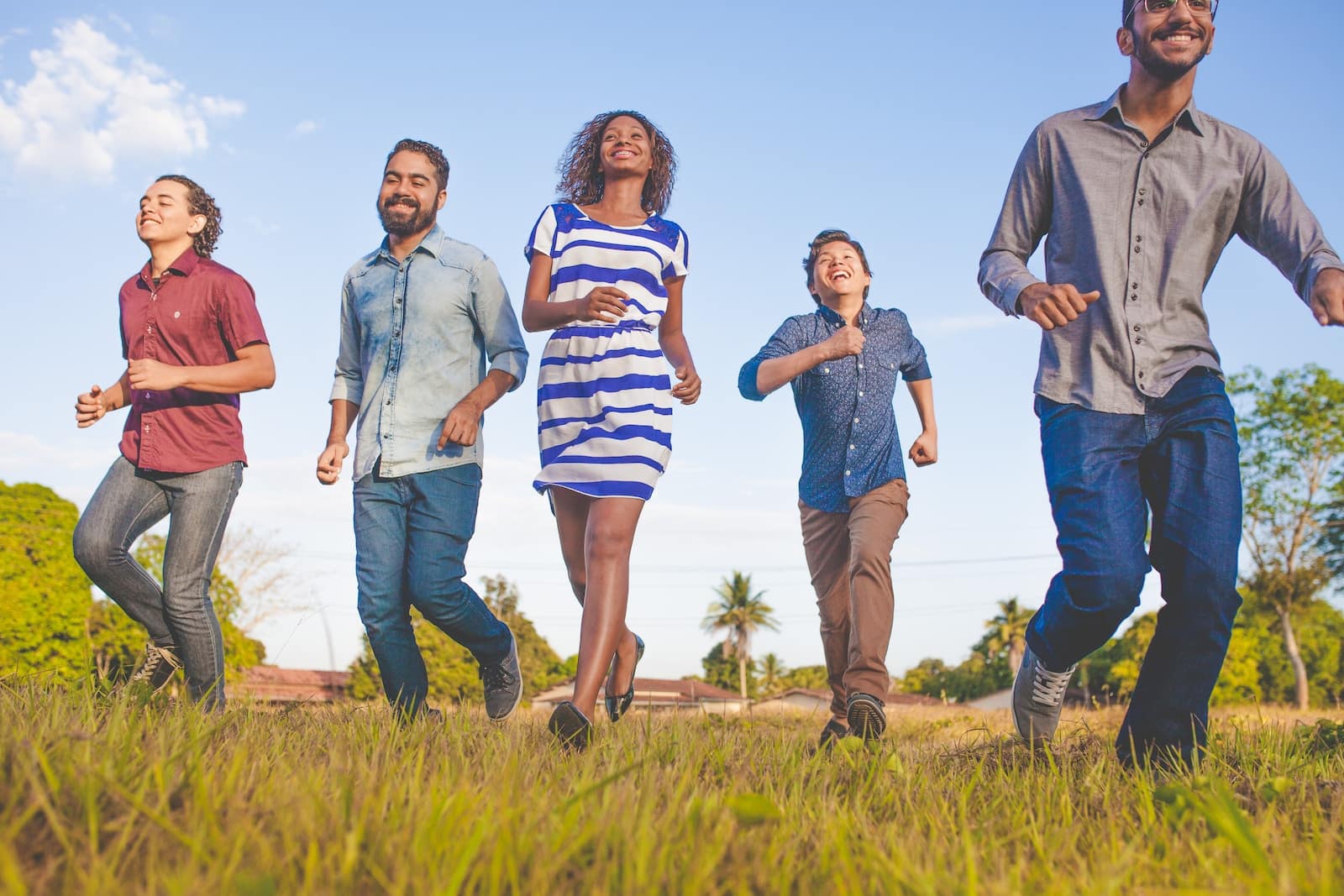 People running on grassfield under blue skies at daytime-blended families
