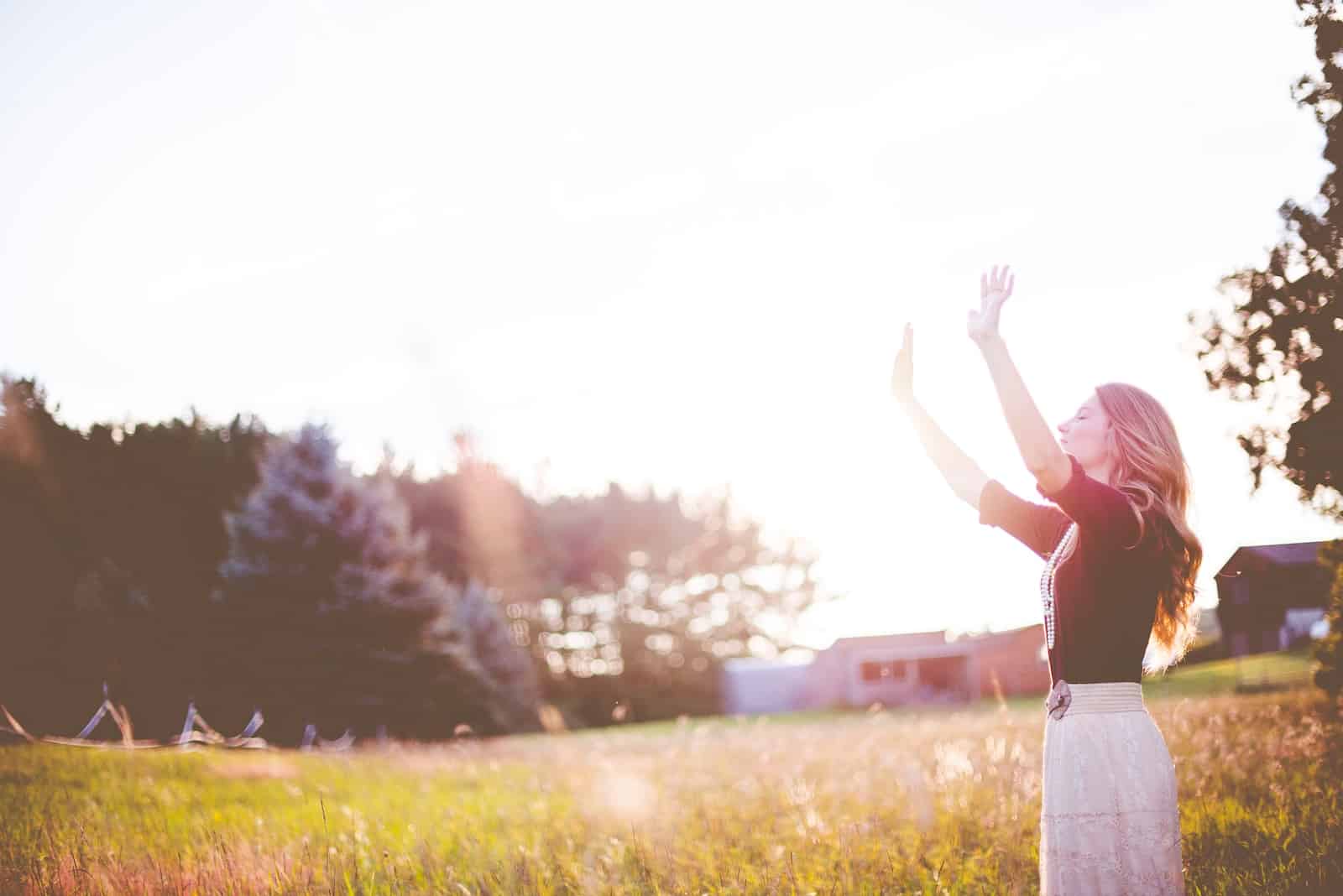 Woman hands up in front of green meadows-be true to yourself