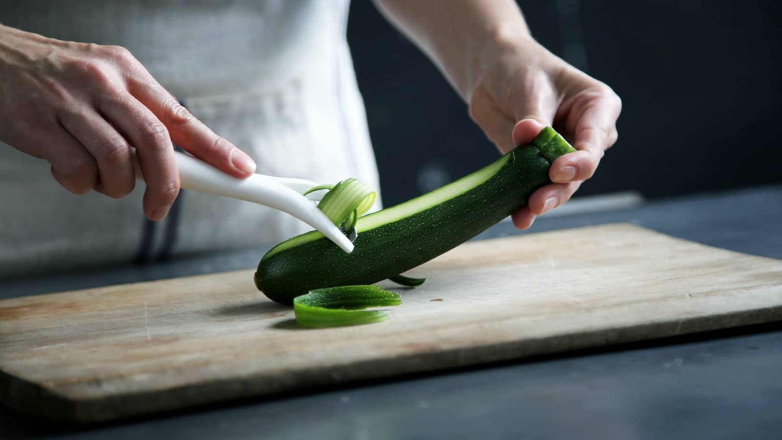 Person pealing green cucumber inside room-benefits of eating cucumber at night