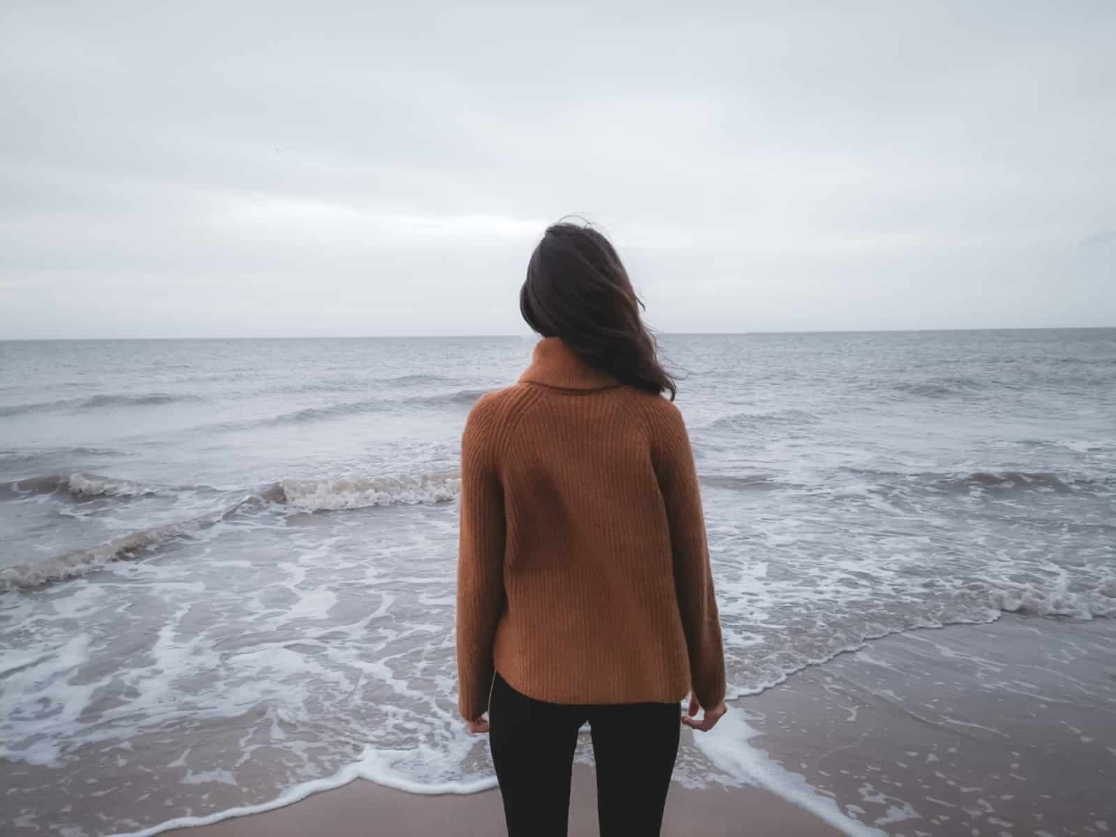A woman standing on a beach looking out at the ocean-conquering anxiety