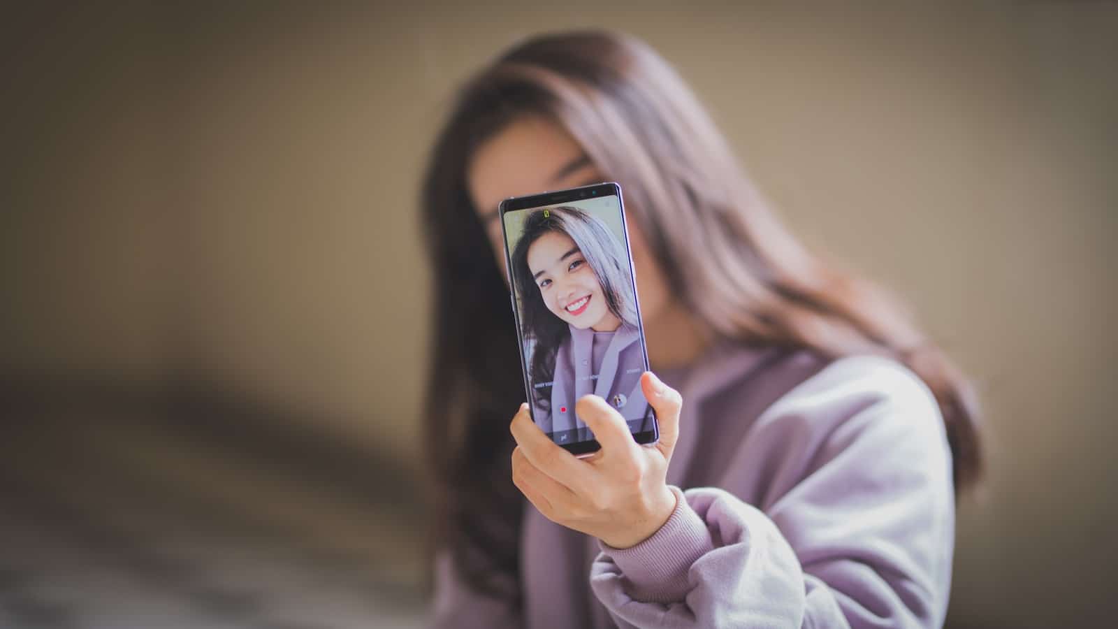 Woman in white long sleeve shirt holding black smartphone