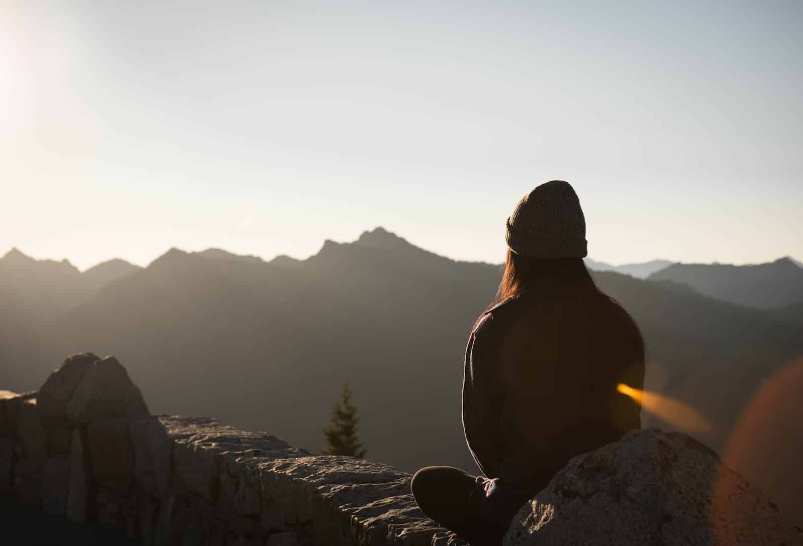 Person wearing knit cap facing mountain-transformative benefits of mindfulness and meditation