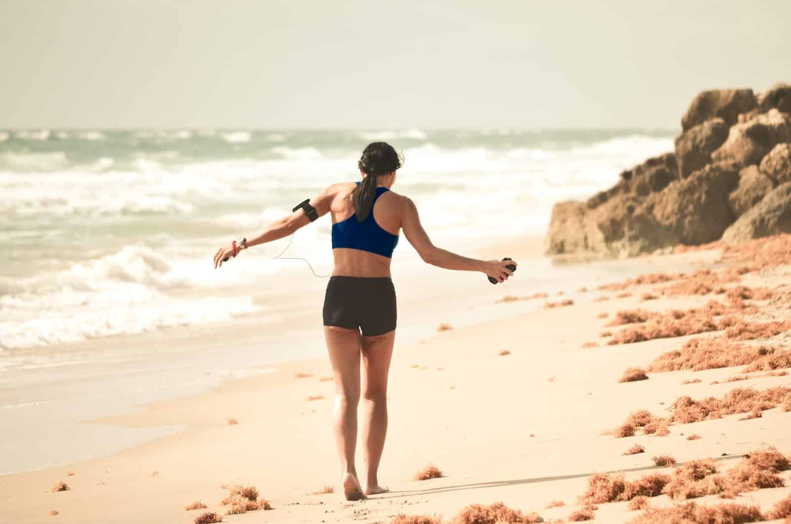 Woman walking on sand near seashore during daytime