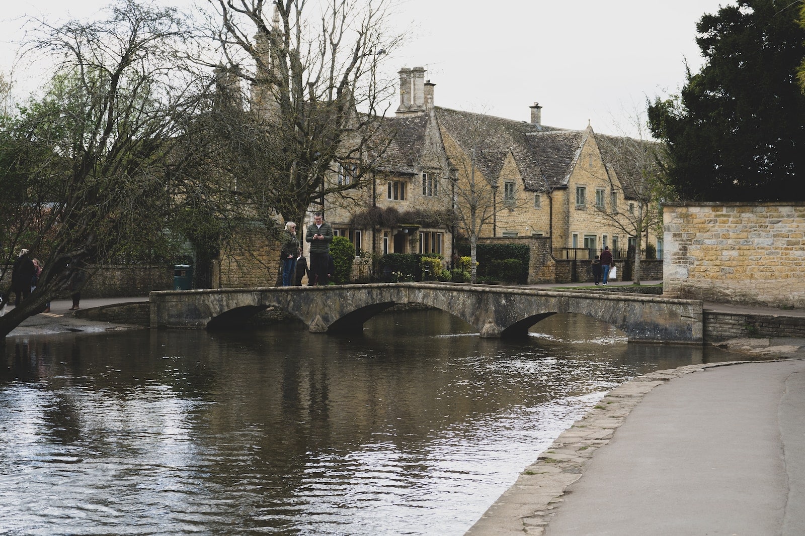 A bridge over a body of water in front of a house-bourton-on-the-water