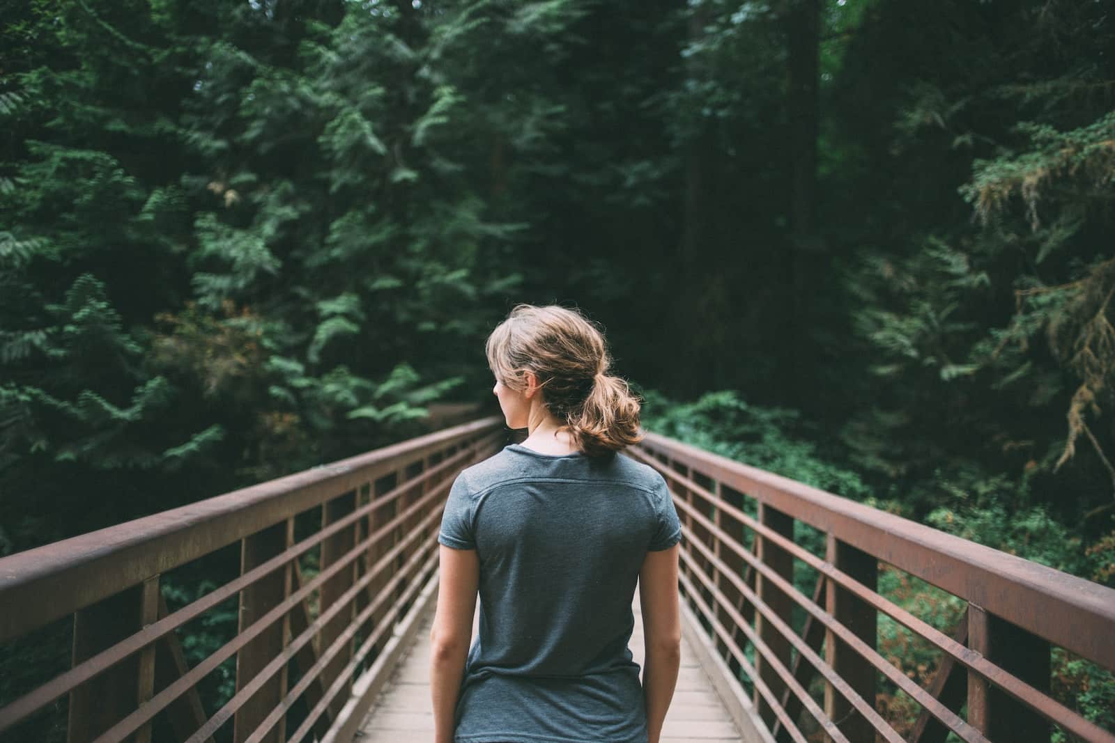 Selective focus photography of woman in black t-shirt standing on bridge-unpack emotional baggage