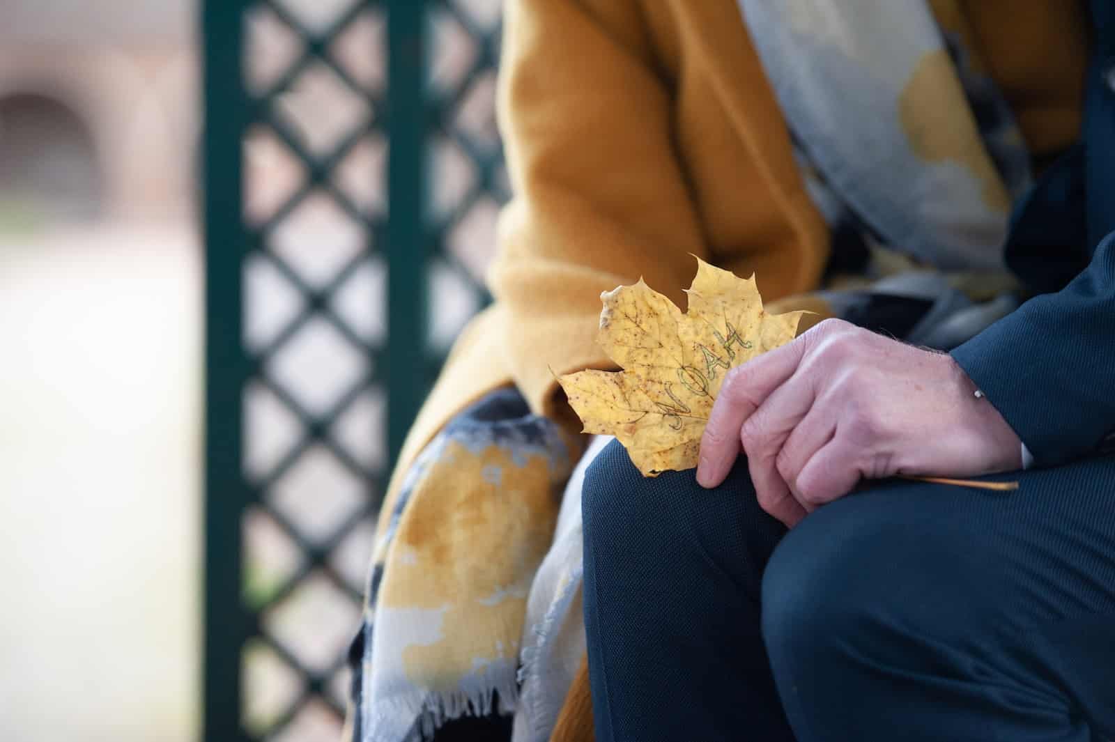 A person sitting on a bench holding a leaf-help a friend with emotional baggage