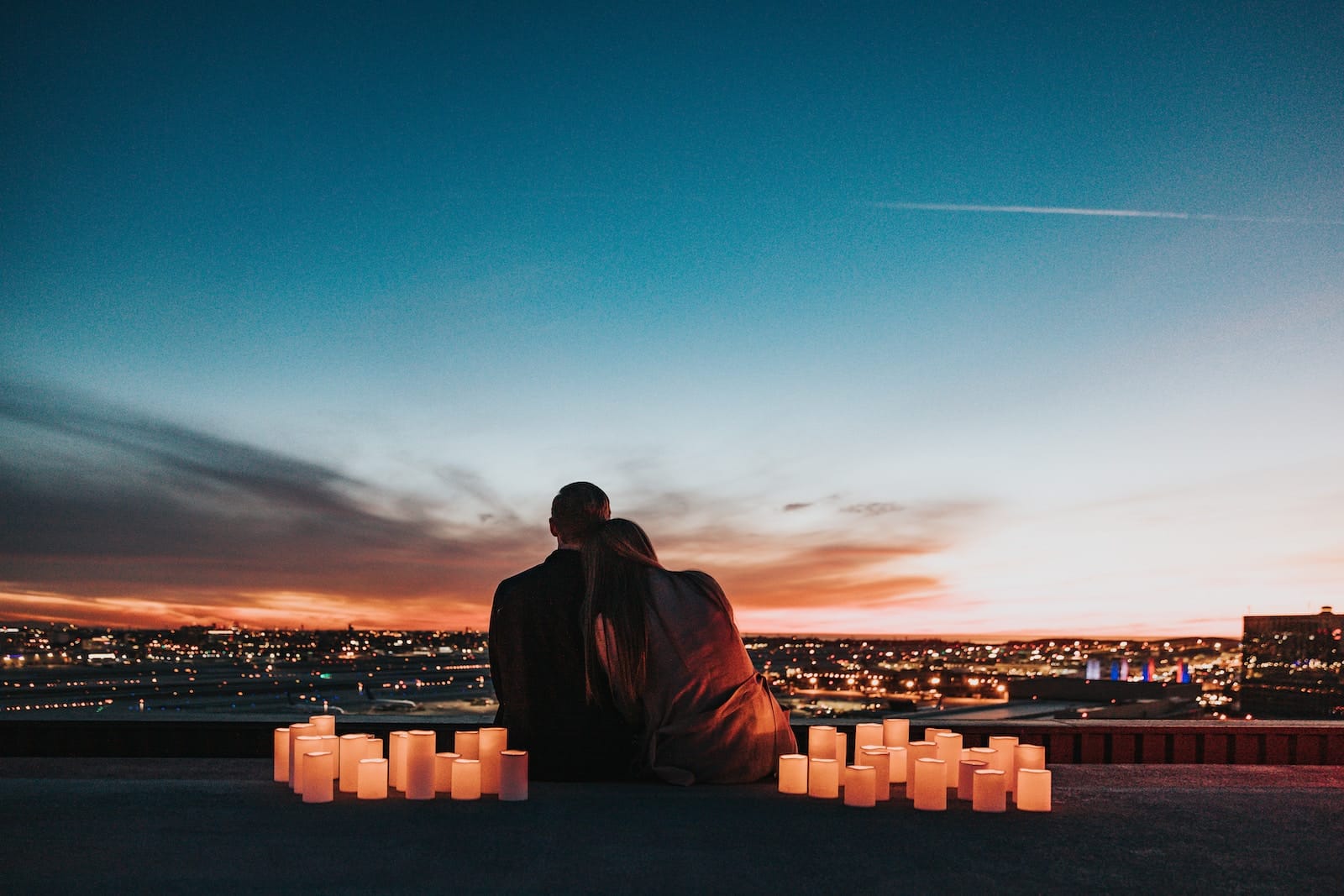Couple sitting on the field facing the city-things to do as a couple when bored
