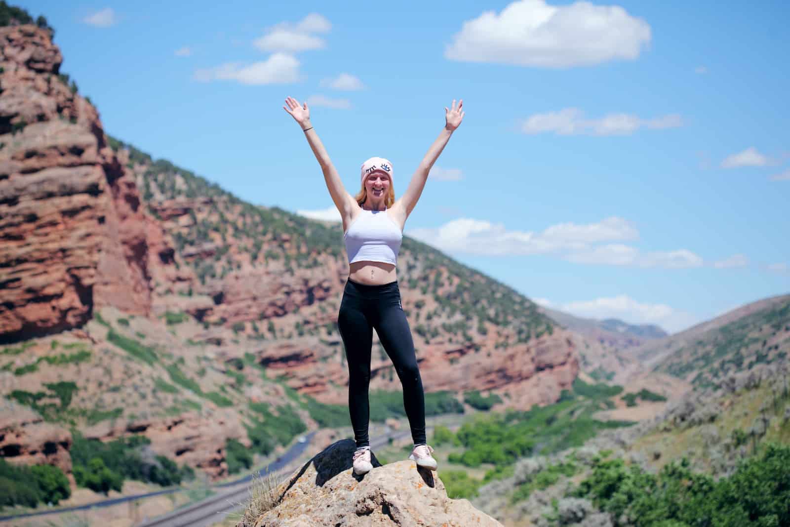 Woman wearing white top and black pants standing on cliff0-achieve goals example