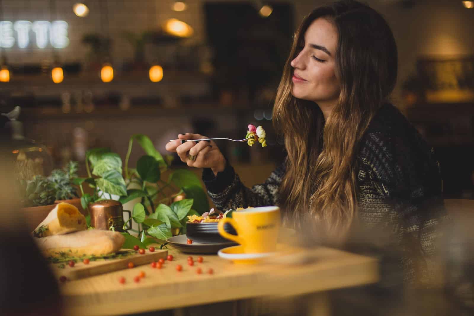 Woman holding fork in front table-intuitive eating meal plan