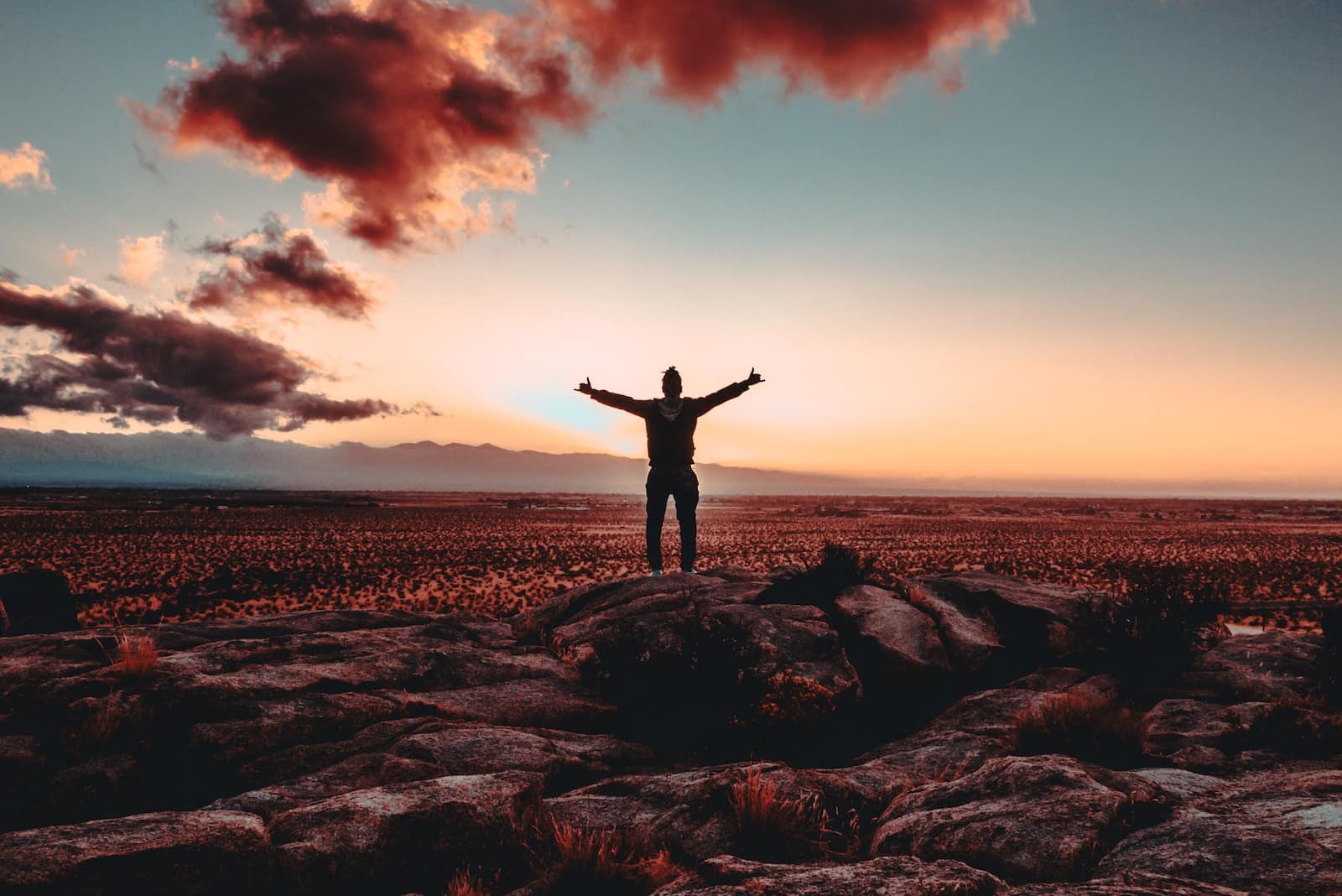 Person standing on rock raising both hands-losing motivation