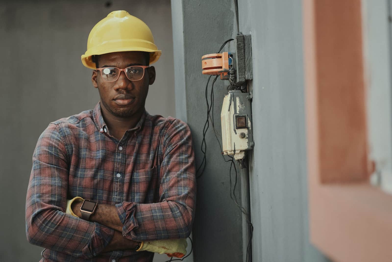 Man in blue white and red plaid button up shirt wearing yellow hard hat holding black-how to motivate boyfriend to get a job