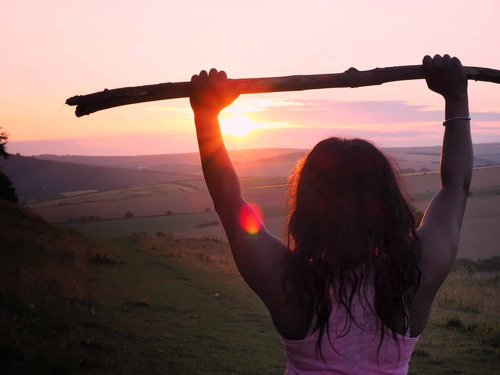 Woman wearing pink tank top holding wood stick during sunrise-people better than me