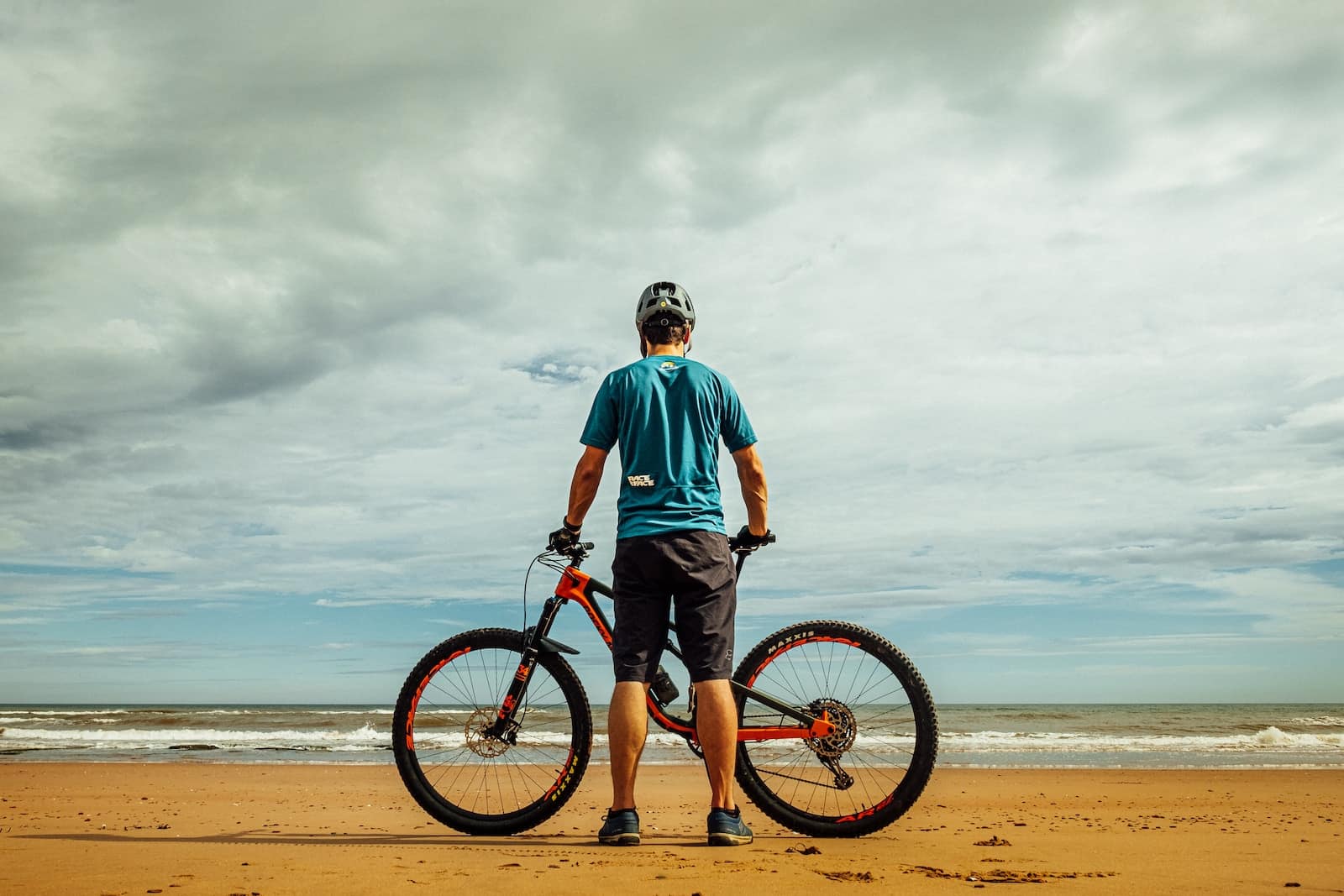 Man standing beside bike on seashore-regularly scheduled physical activity