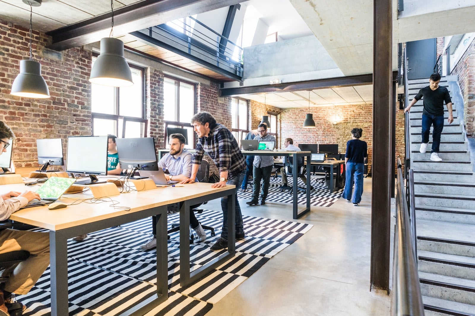 Man standing beside another sitting man using computer-business startup