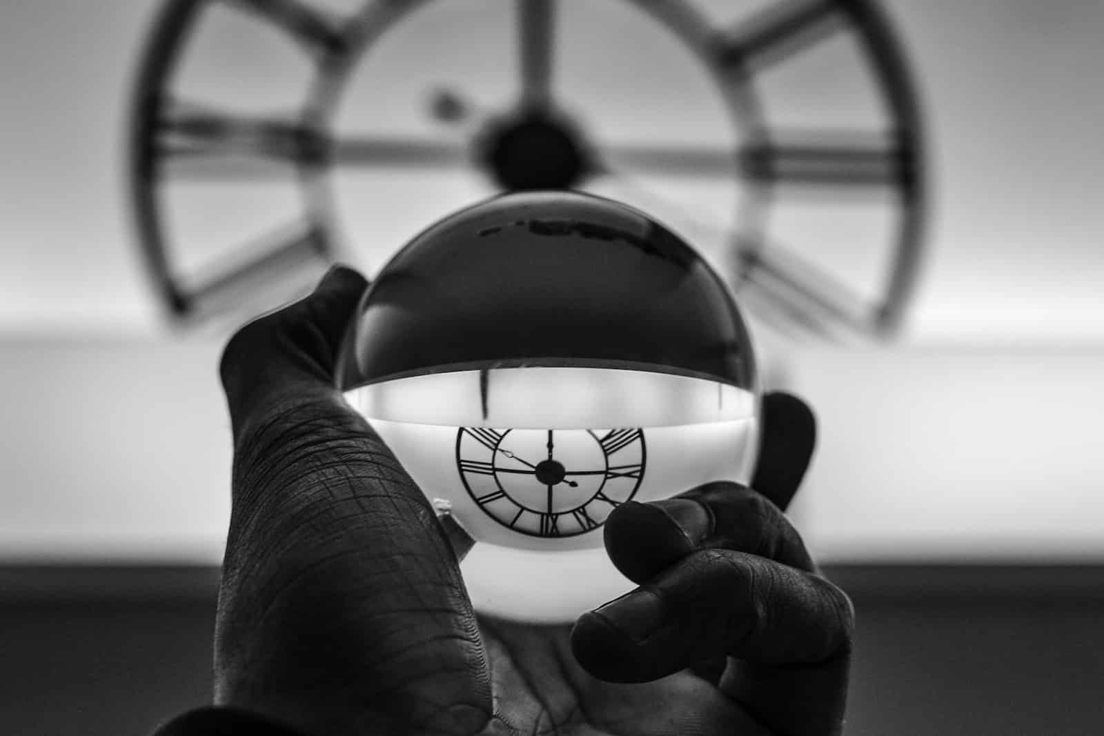Grayscale photography of person holding glass ball