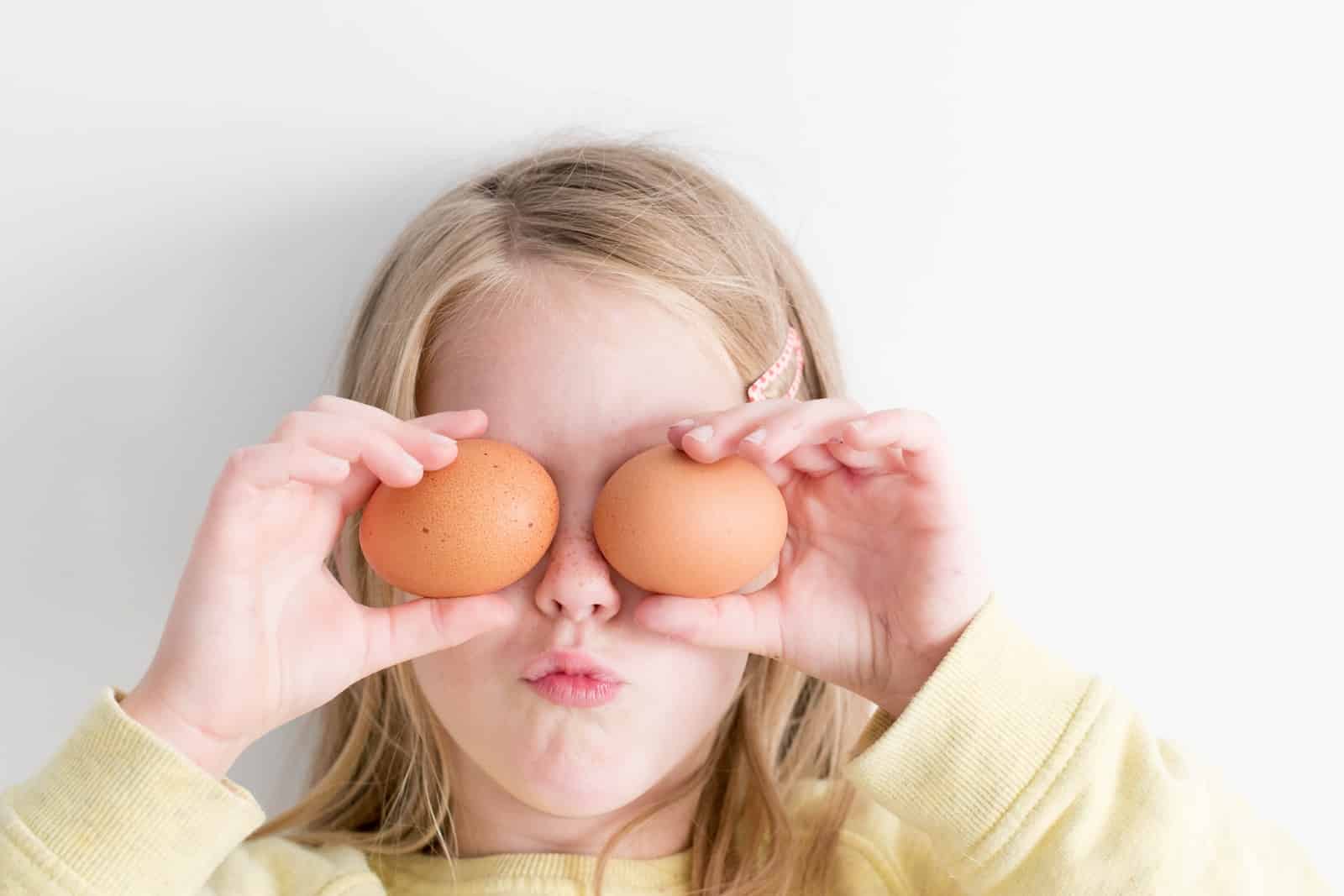 Girl holding two eggs while putting it on her eyes-why do i crave eggs