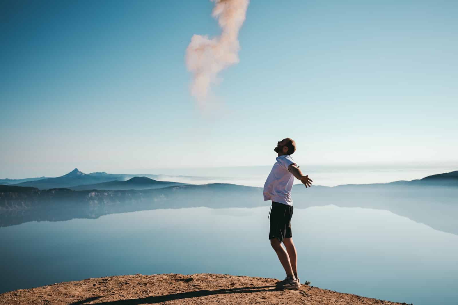 Man standing on sand while spreading arms beside calm body of water-how to master your mindset