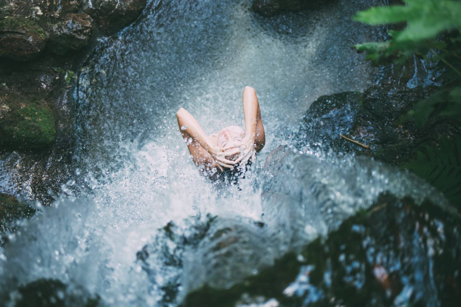 High-angle photography of woman bathing below waterfalls during daytime-why does taking a shower feel like a chore