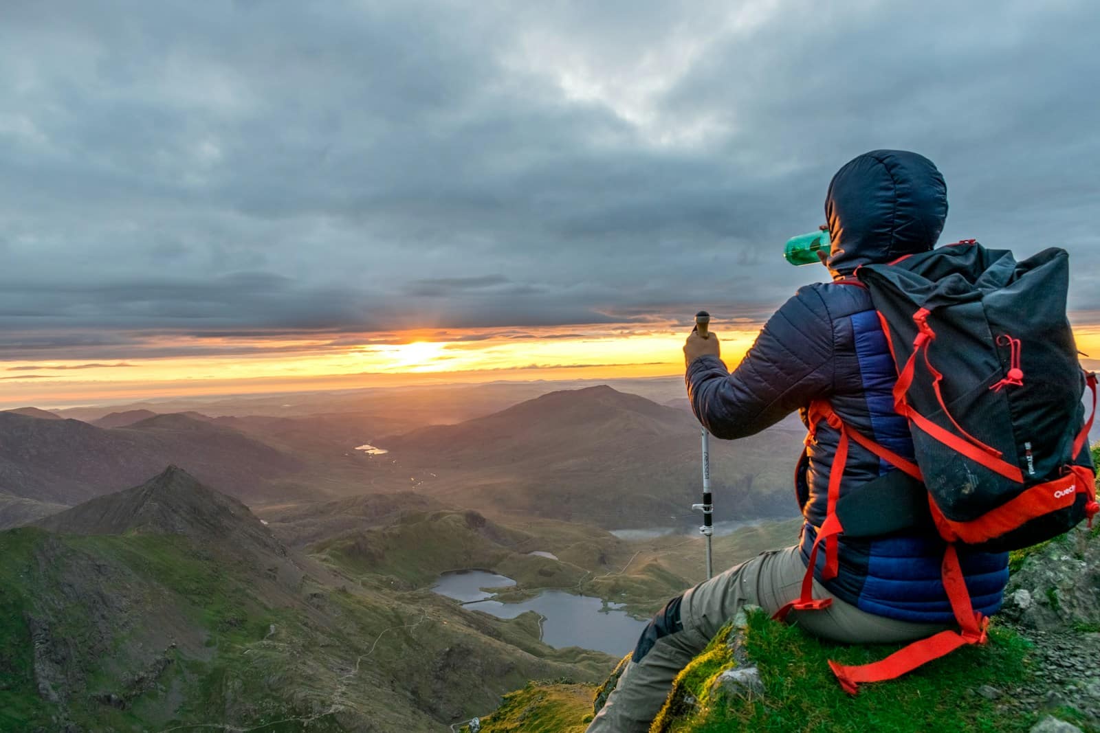 Man sitting on cliffhanger looking at mountain under gloomy clouds-you're doing better than you think