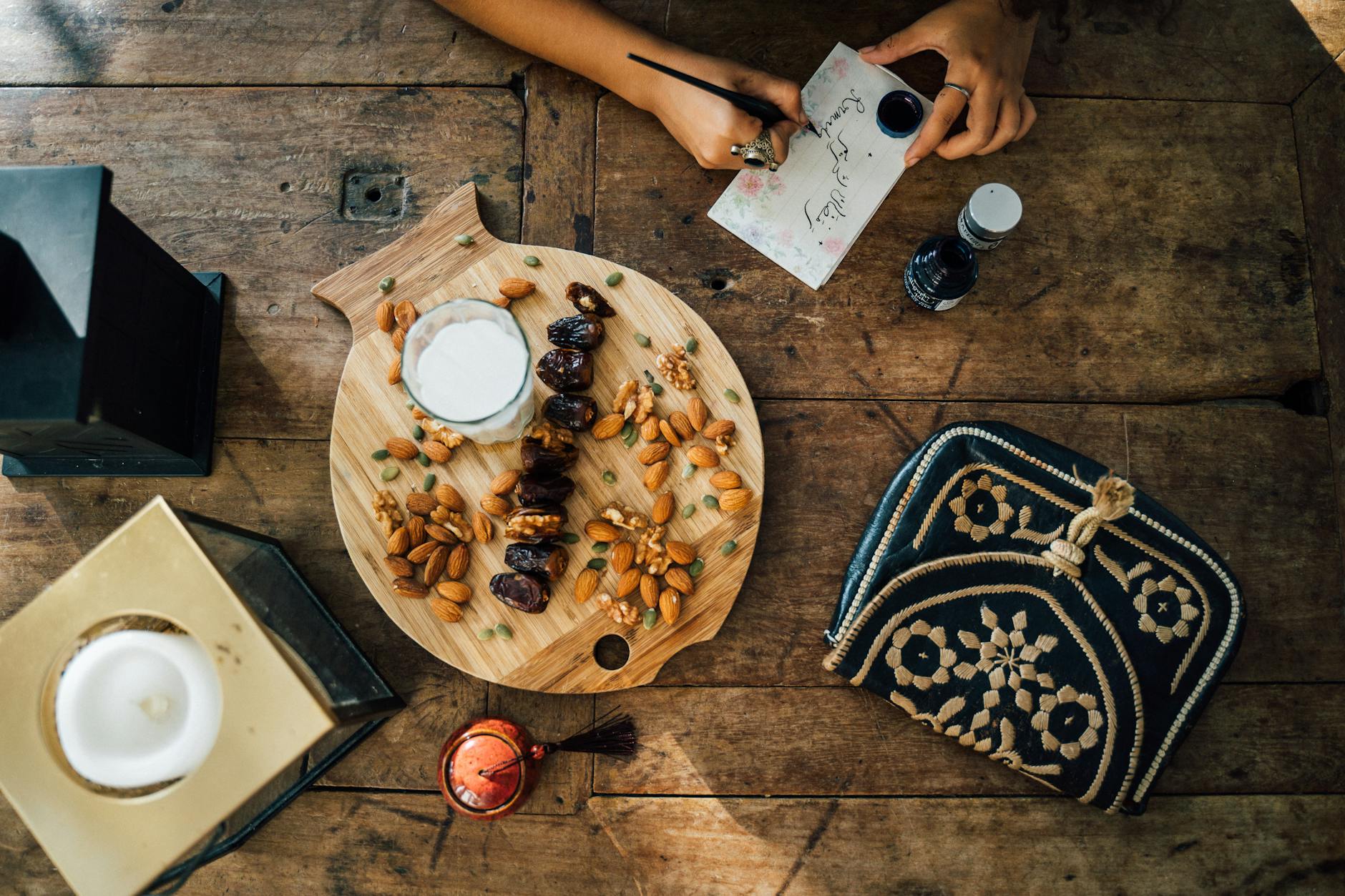 A wooden board with almonds and dates near the person writing on paper-can almond milk cause diarrhea