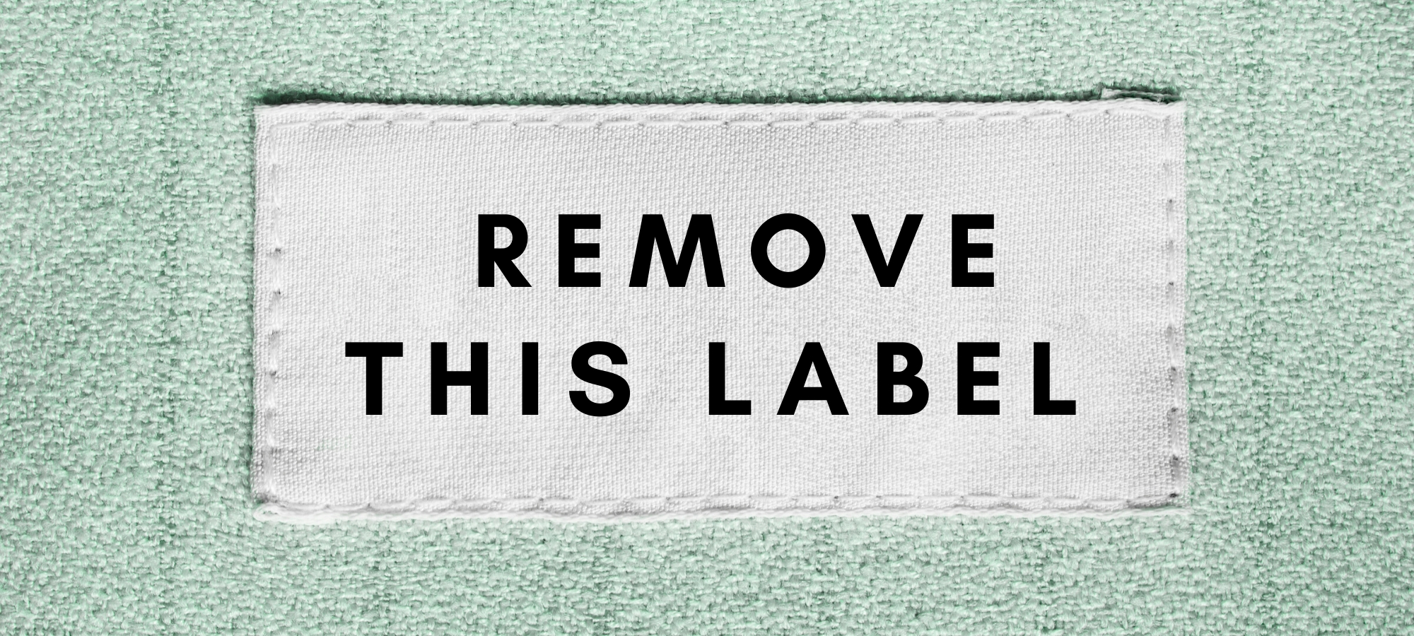 There is a white label that reads "remove this label" on a light blue fabric. It is meant to symbolize the labels of high low functioning autistic person with autism on the autism spectrum. Also, it is referencing the labels of disorder, mental illness, and disability as they apply to autism asperger's aspie.