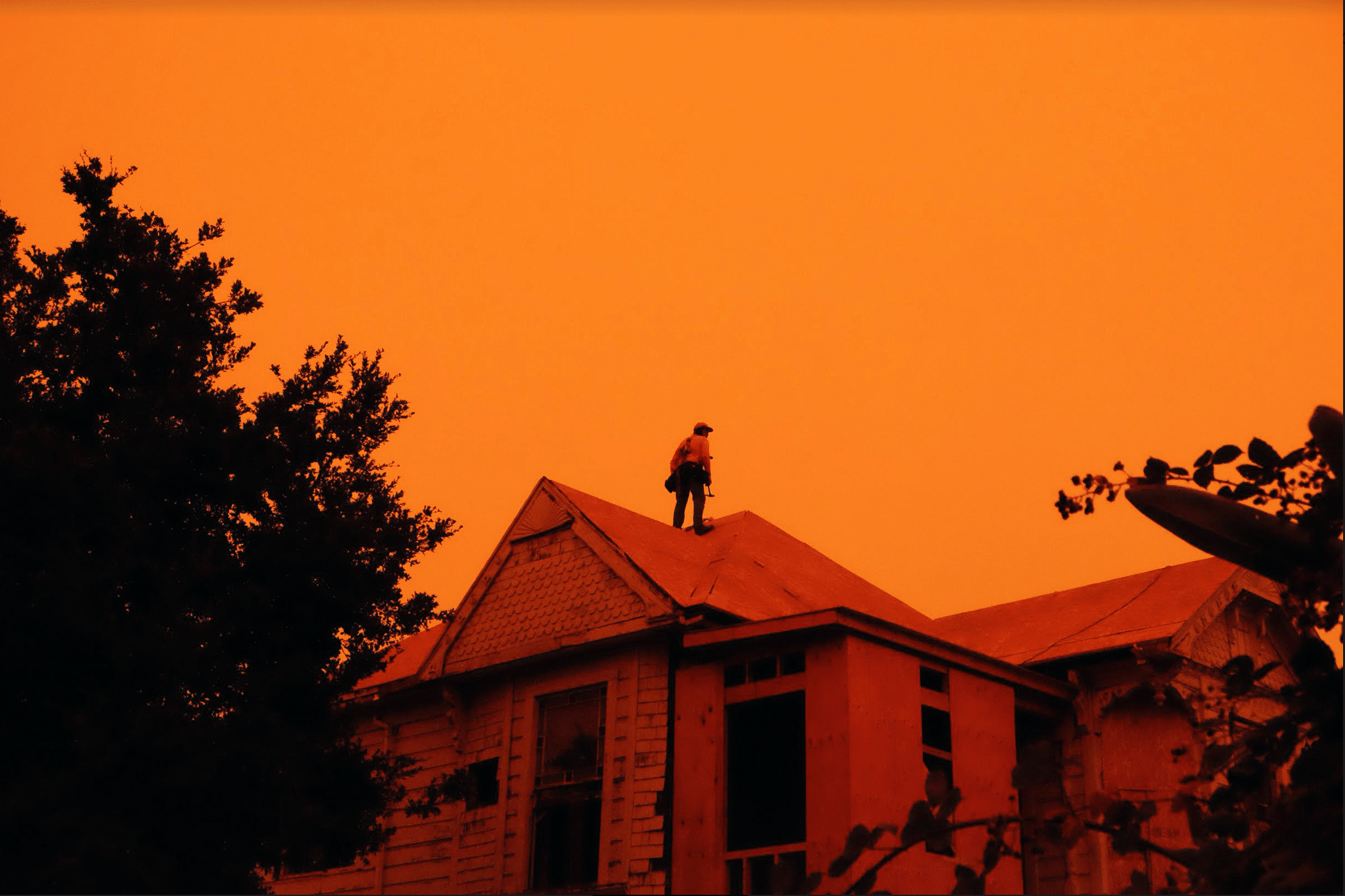 a man standing on the roof of a house in orange light