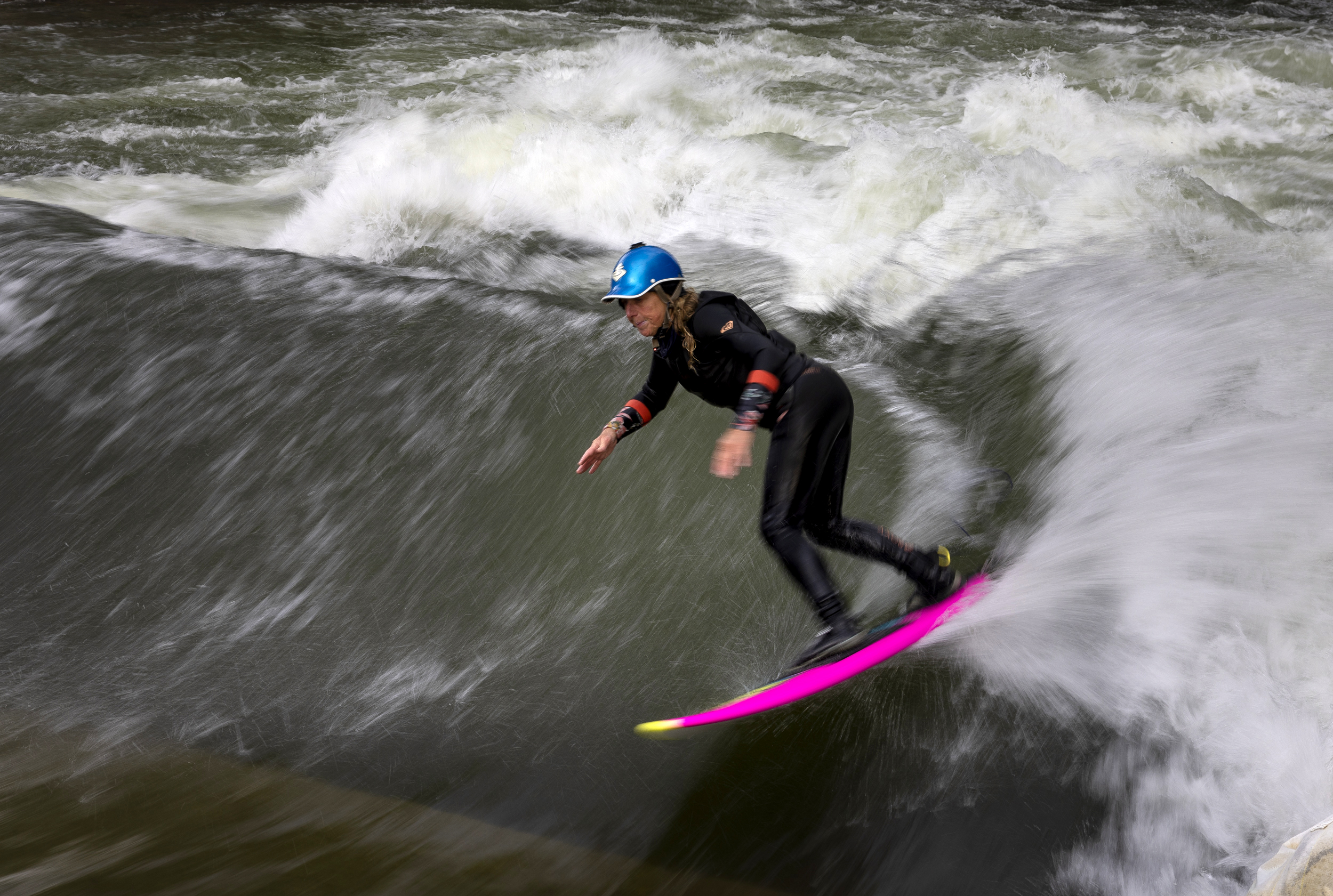 A motion blur of a whitewater river as a surfer rides a wave