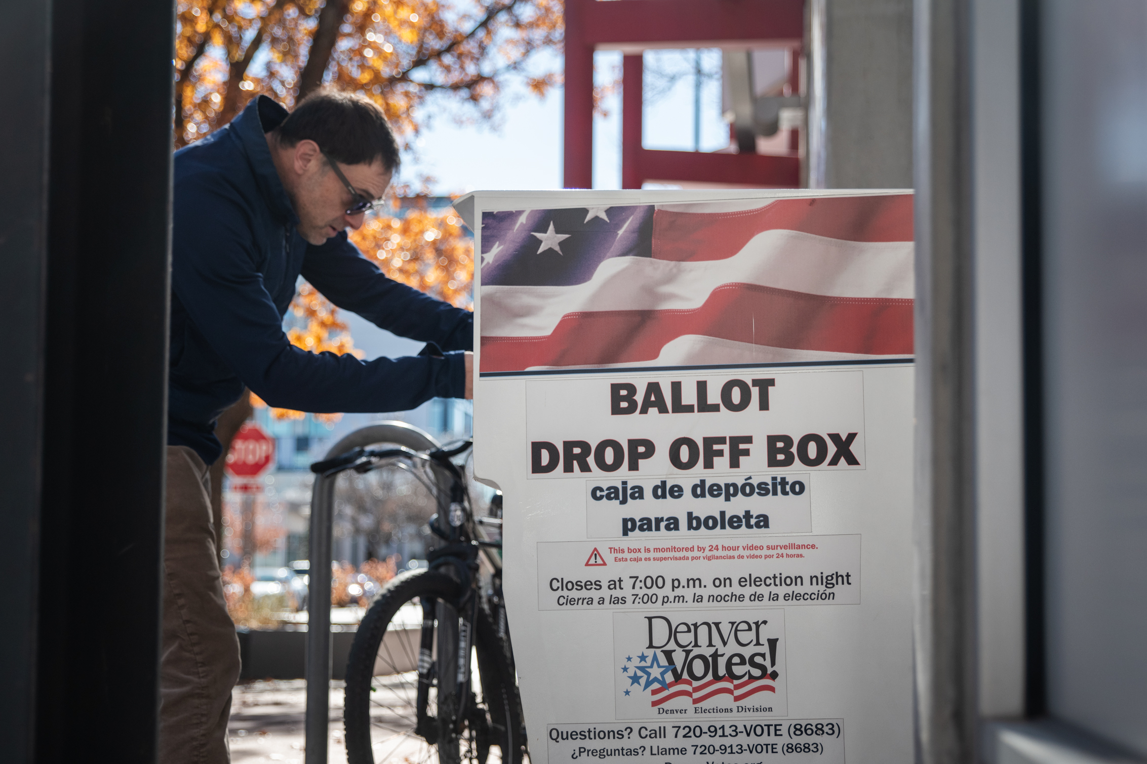 A person places a ballot in a drop off box