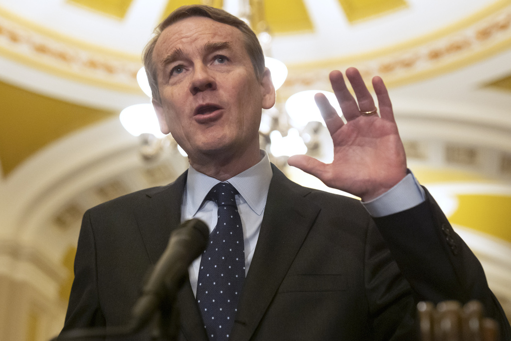 Michael Bennet speaks into a microphone inside an ornate building.