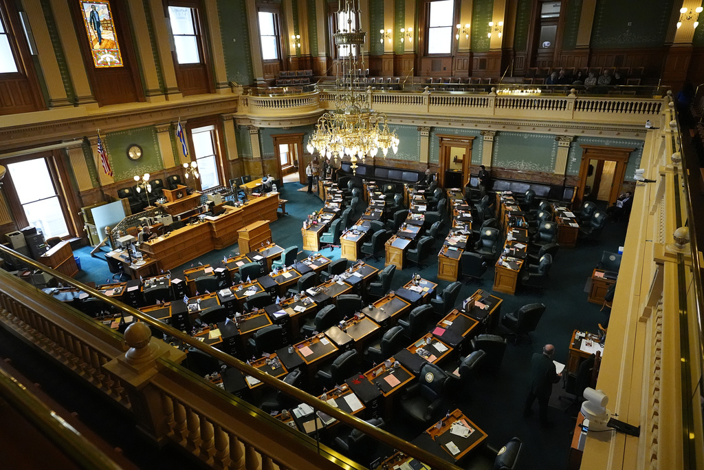 An aerial view of the House floor inside the Colorado Capitol. Empty desks are in curved rows that face the front.