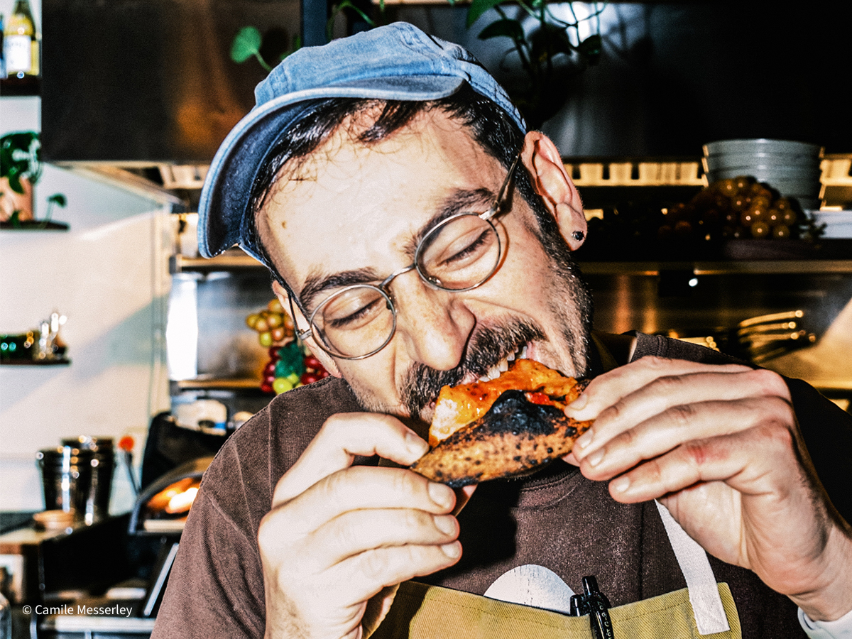 Jules eating a pizza in a restaurant.