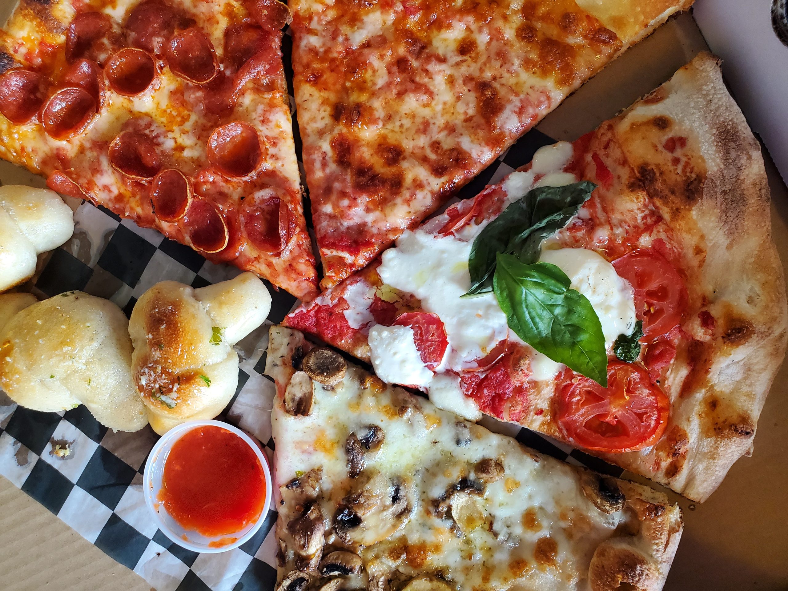 Slices of cheese, pepperoni, and burrata pizza from Slice & Pie