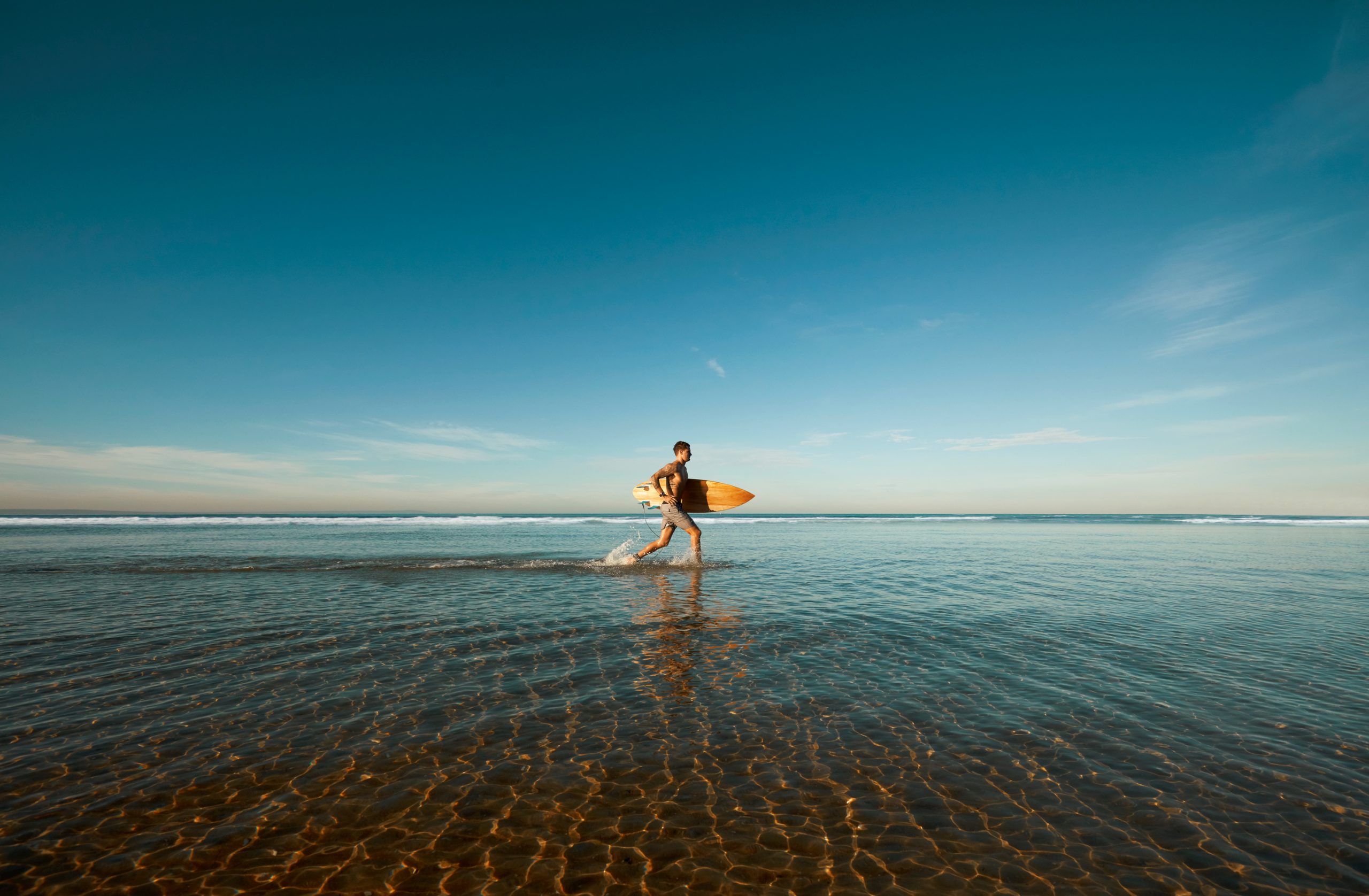 Young man running with surfboard at the beach