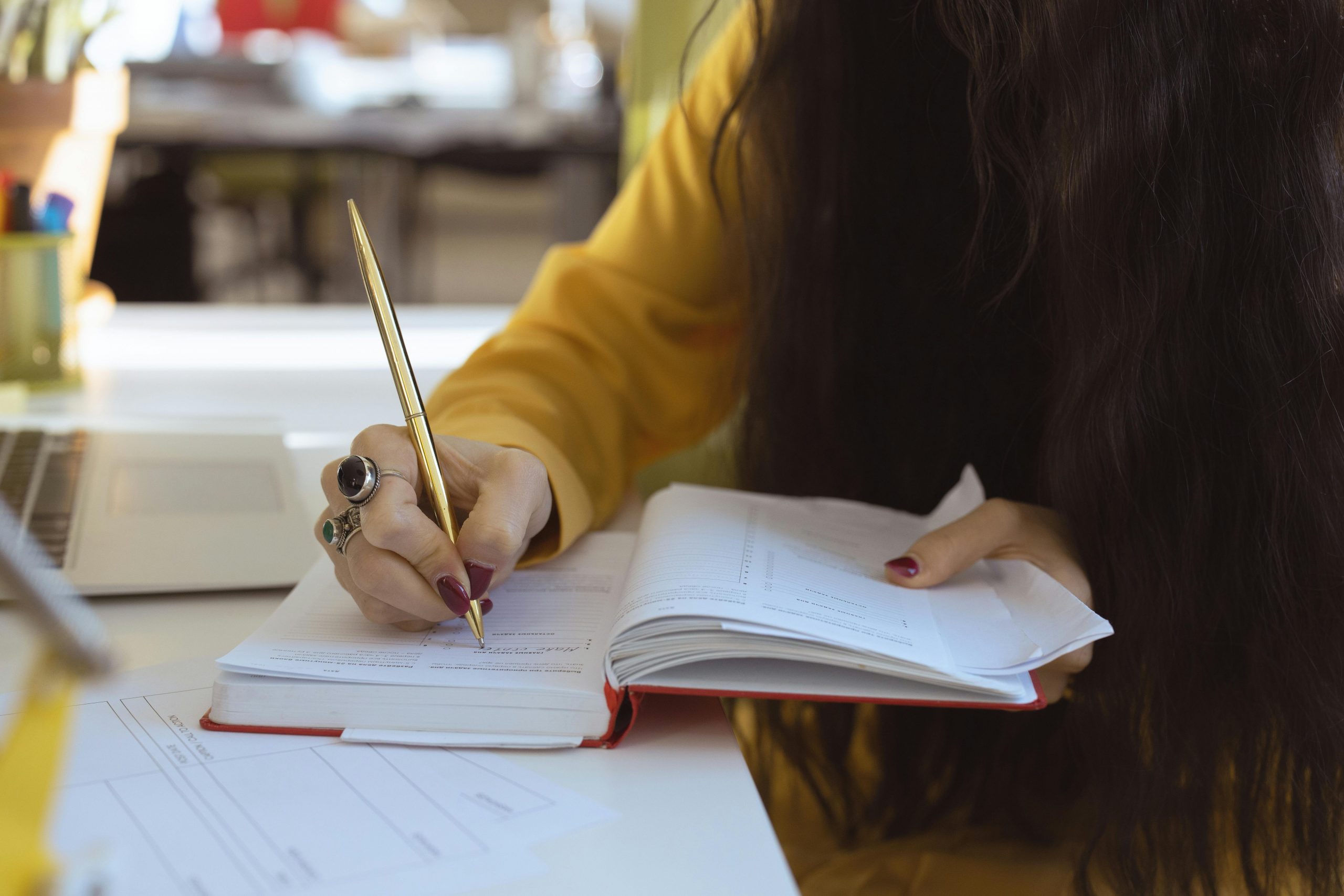 Close-up of a woman writing in a notebook, focusing on hand and pen, suitable for productivity themes.