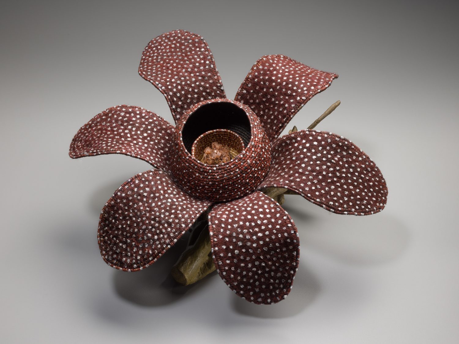 Woven brown basket in the shape of a flower with white spots.