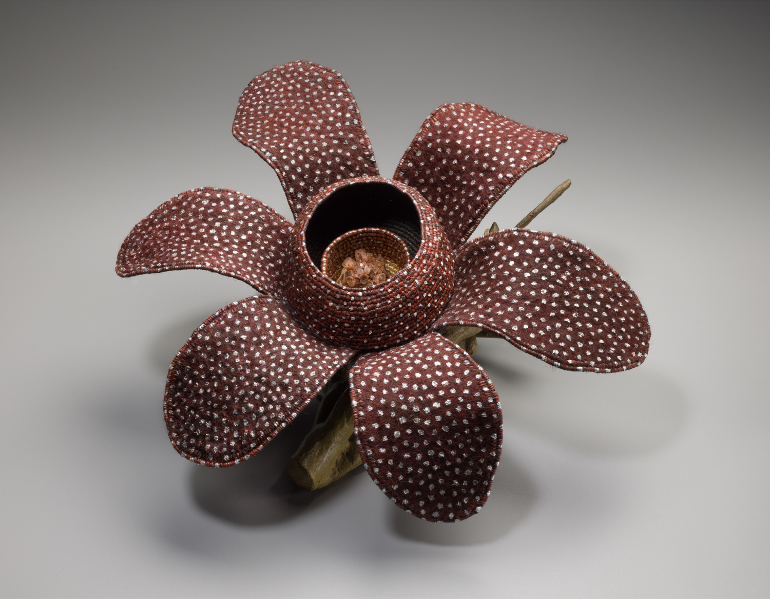 Woven brown basket in the shape of a flower with white spots.