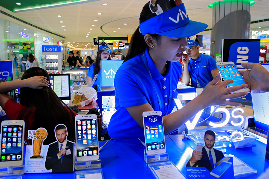 A sales person shows a buyer the features of Vivo mobile phone displayed at a stall inside a Cyberzone of the SM Mall of Asia in Pasay city, metro Manila