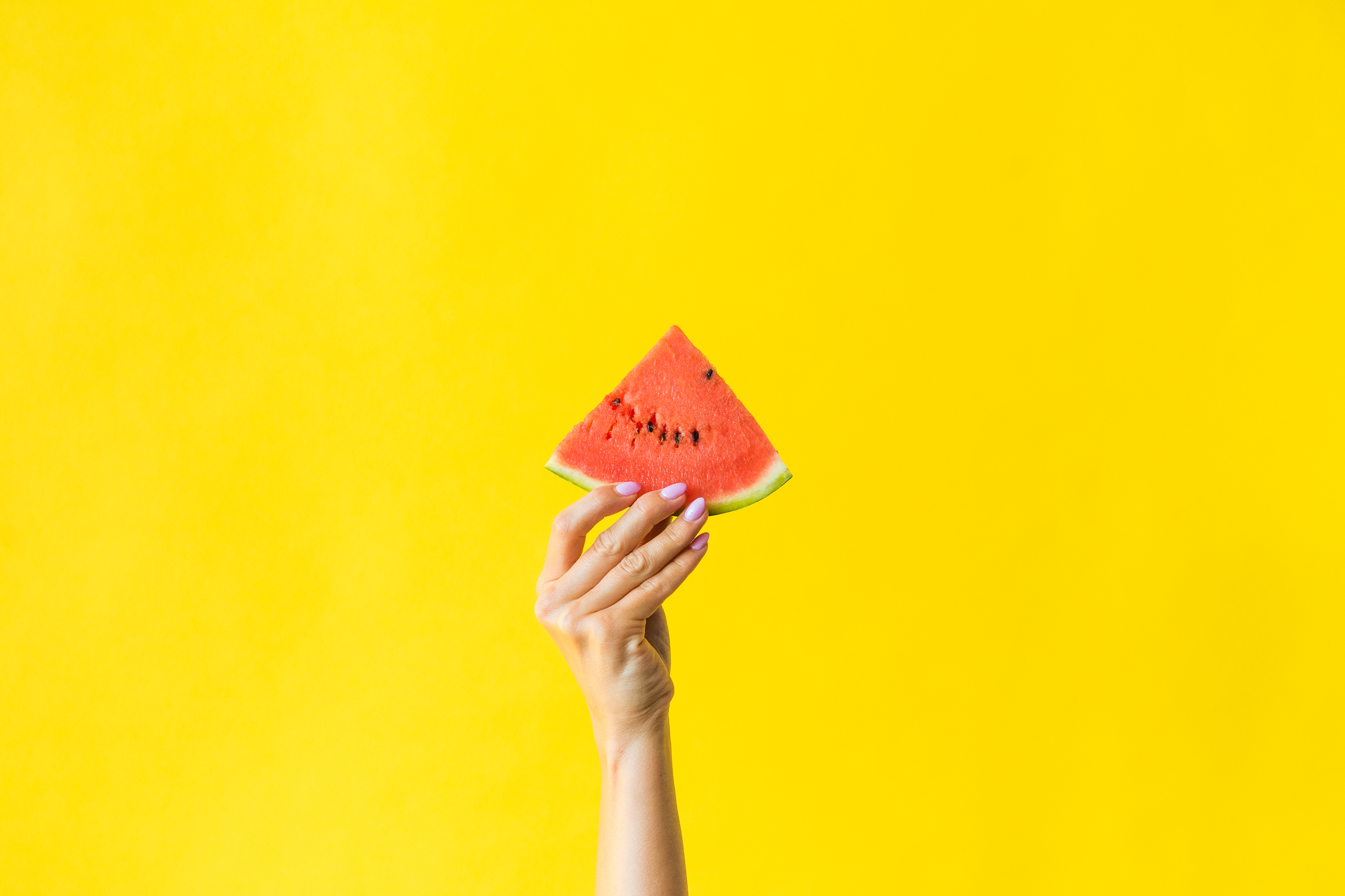 Slice of Watermelon in Woman Hand on Bright Yellow Background Free Photo