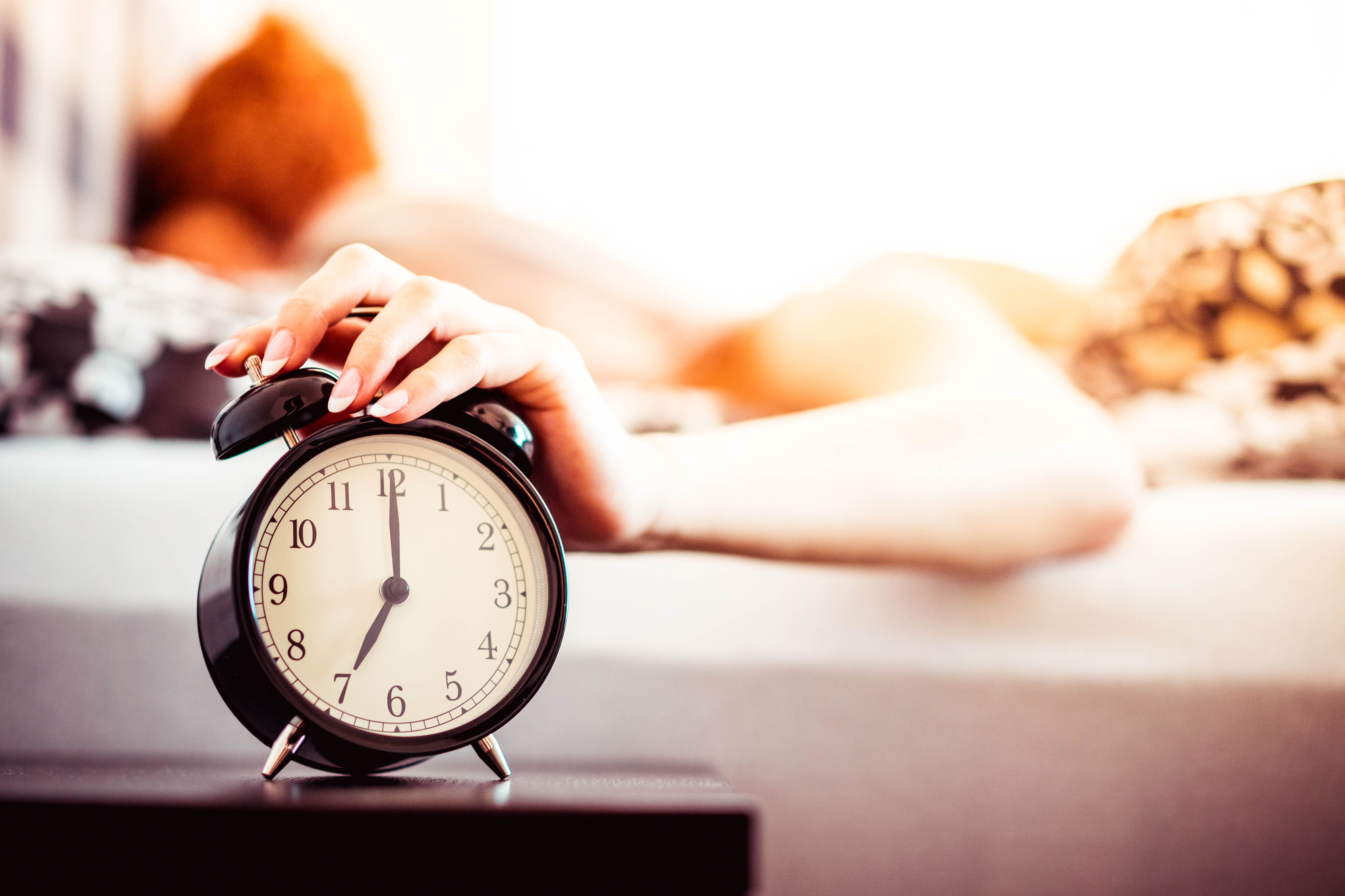 Woman Shutting Off Ringing Alarm Clock From Bed Free Photo