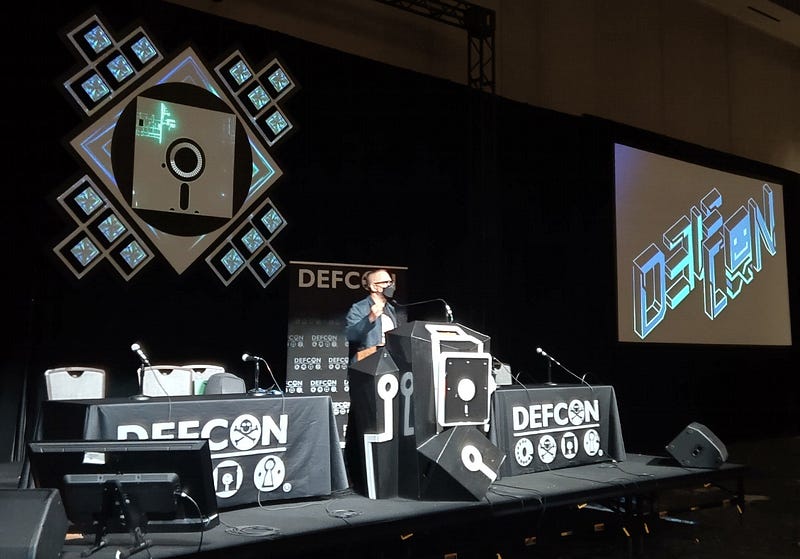 A photograph of me speaking on stage at Defcon 31.