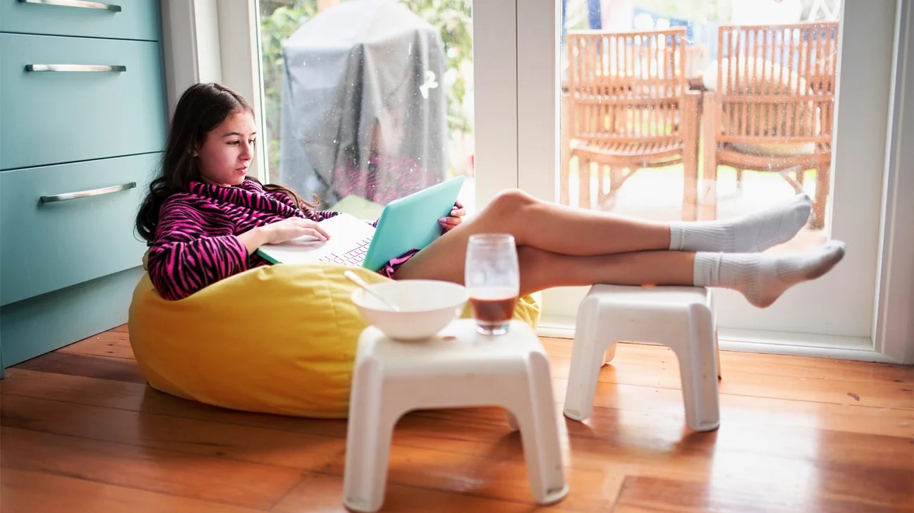 teenage girl on her laptop with snack nearby