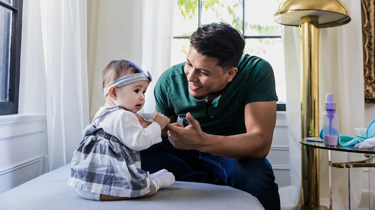 father playing with sitting baby daughter