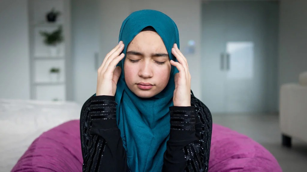 a woman holding her temples because she has a headache from cytokine release syndrome