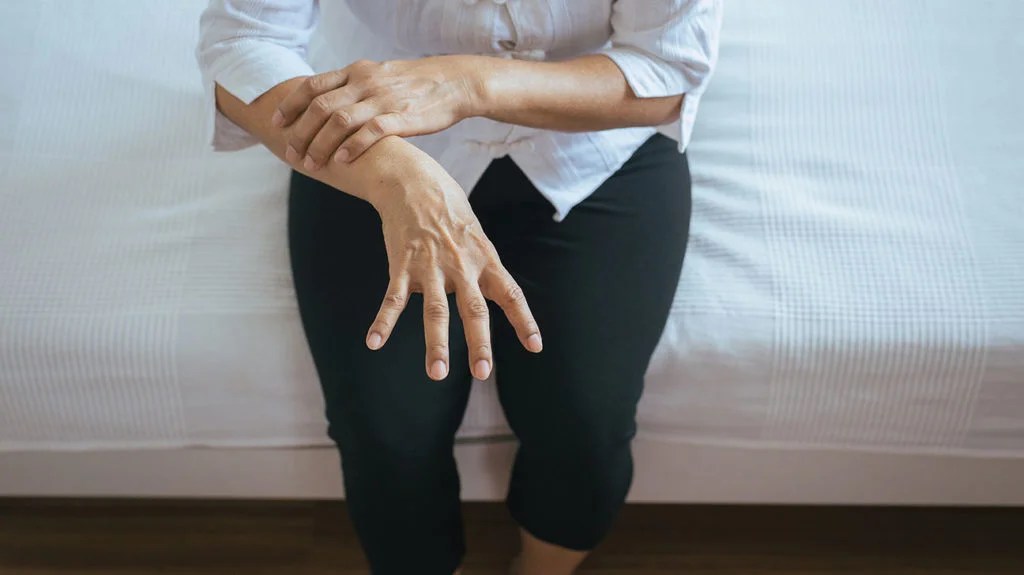 A woman holds her arm after experiencing one of her body tremors.