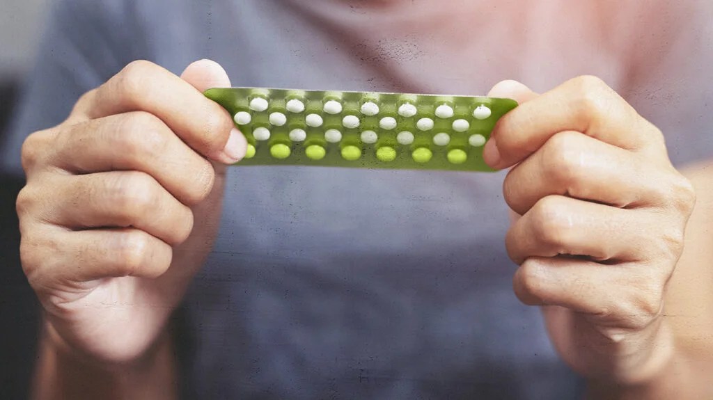 A photo of a woman holding a blister pack of birth control pills to accompany the article 10 most common birth control pill side effects