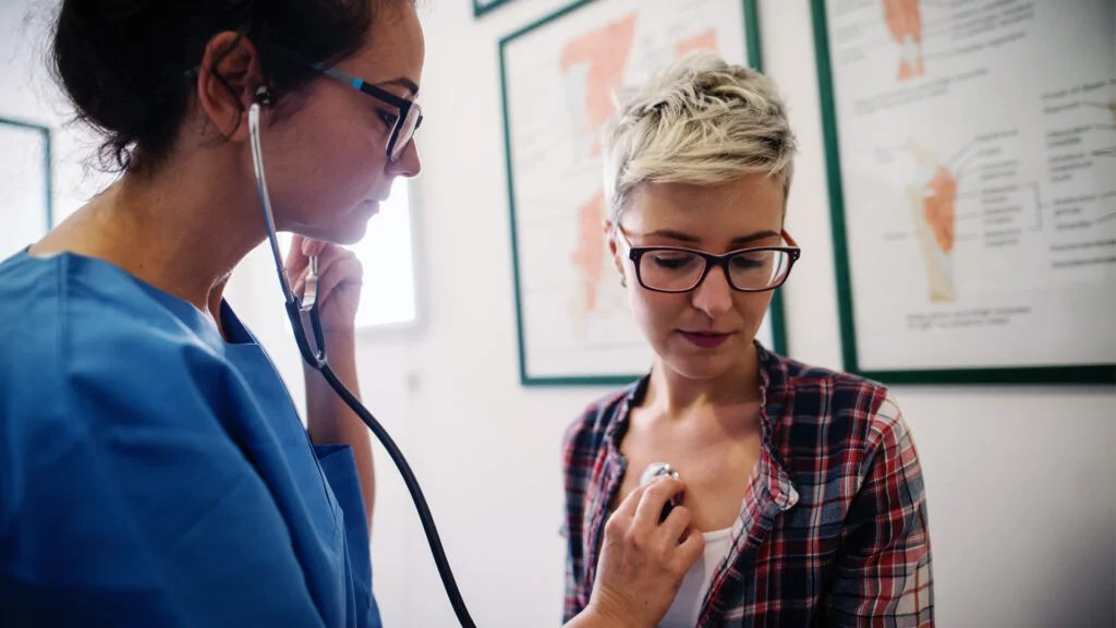 A doctor checking someone's heart with a stethoscope