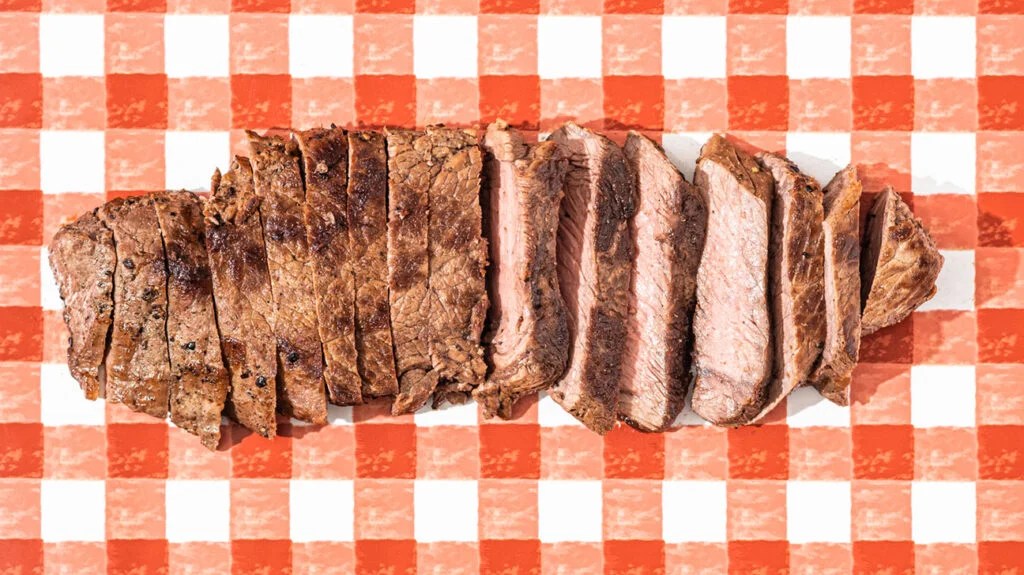 Red meat sliced on a picnic-style table cloth