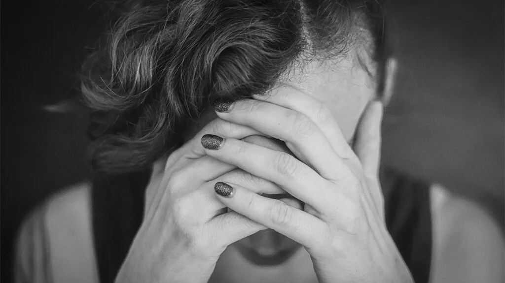 Black & white image of a female with her head in her hands