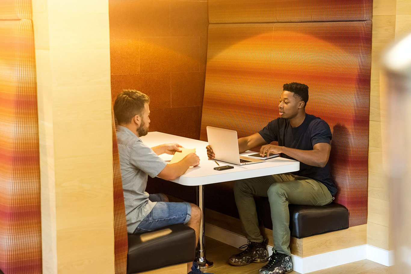 Two men sit in a booth discussing technology