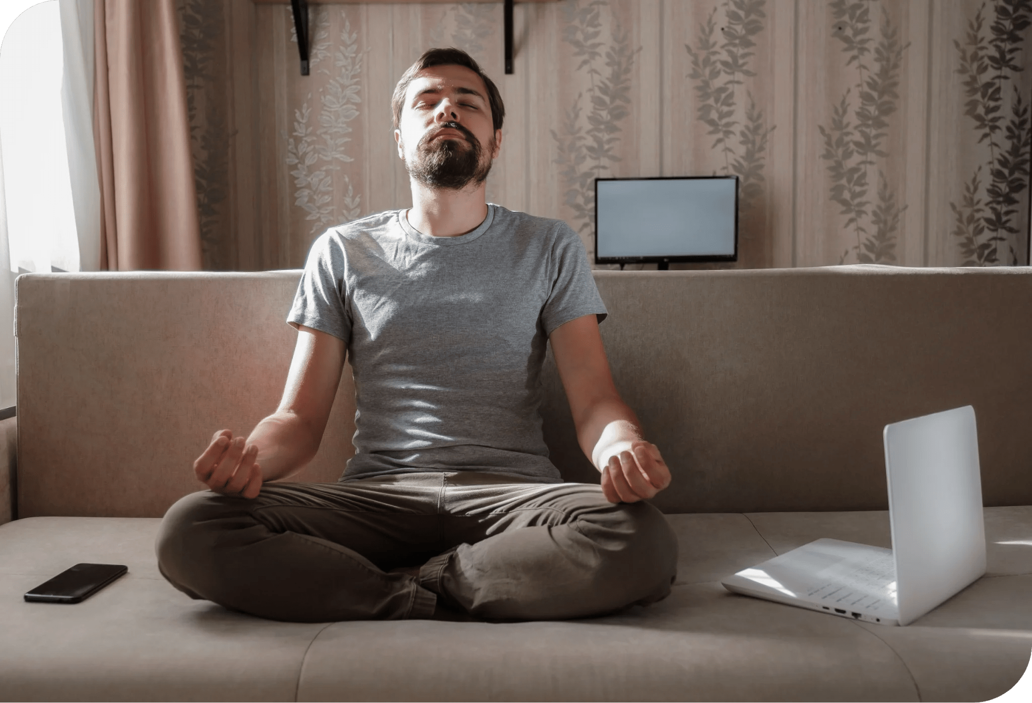 Man meditating next to his laptop.